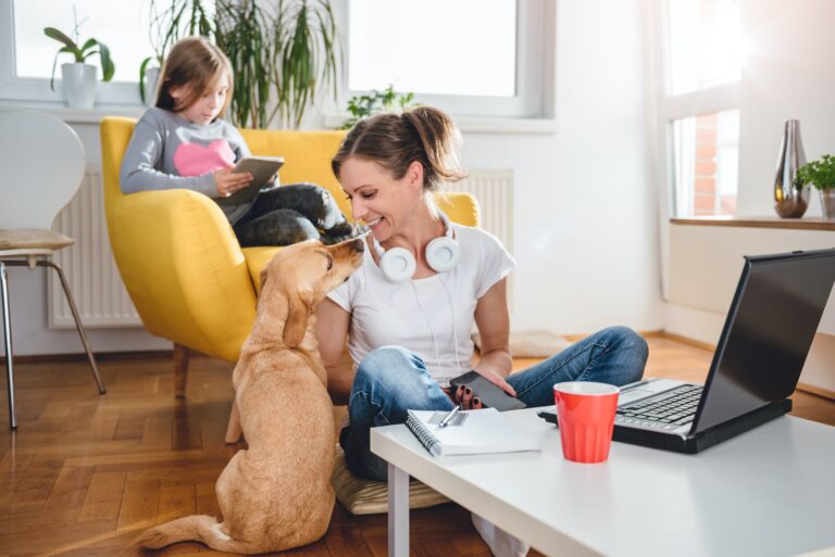 Woman sitting on the floor and Stroking dog at home while daughter sitting on the armchair and using tablet