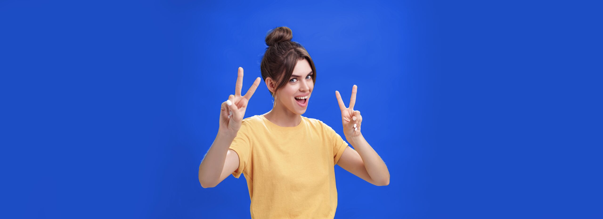 Indoor shot of enthusiastic excited and happy daring girl with combed hair tattoo and cute diasdema showing peace signs bending backwards standing in cool energized pose over green background. Lifestyle.