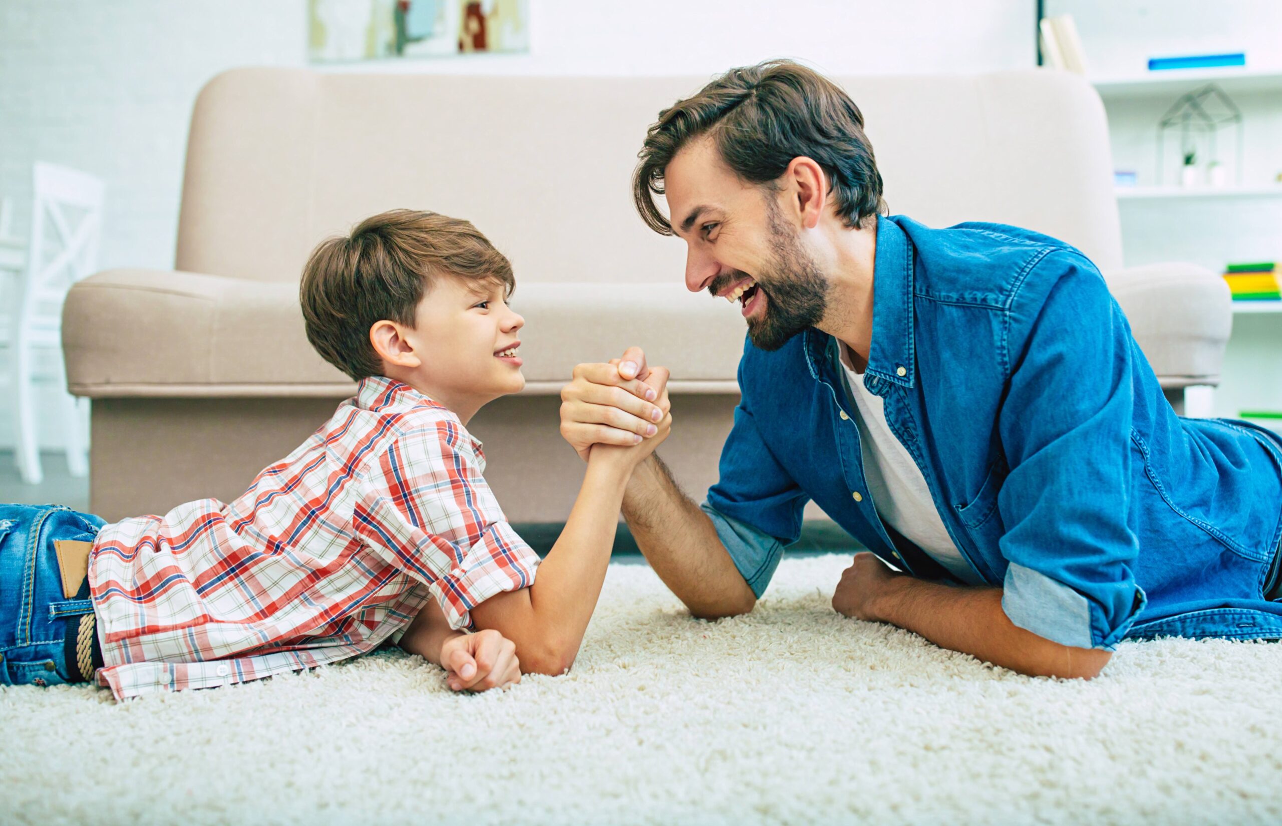 Handsome happy father and his smiling son are lying on the floor at home together